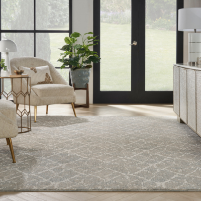 Elegant living room with a light geometric rug, cream armchair, and garden view through dark-framed French doors.
